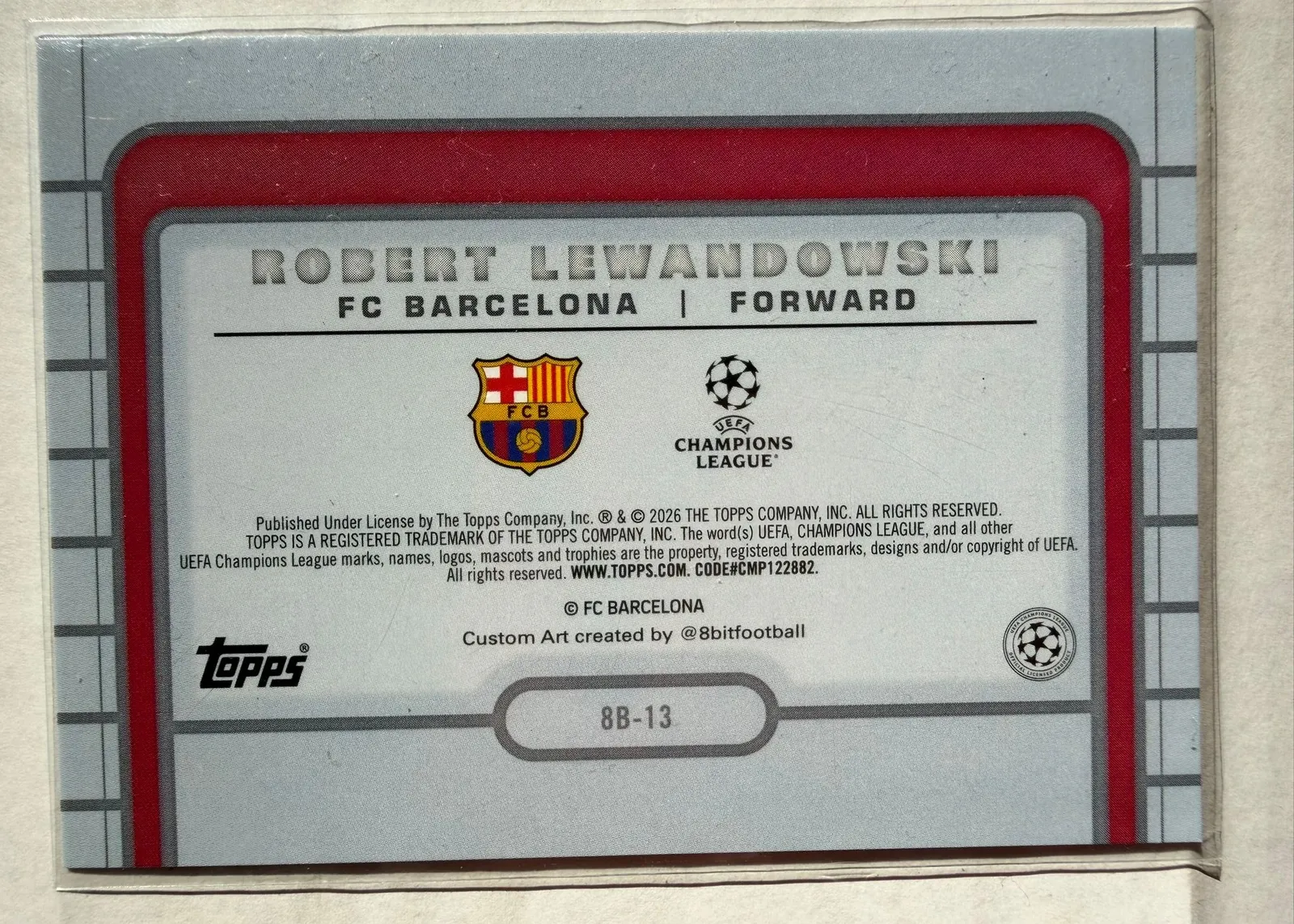 Robert Lewandowski, Topps UEFA Club Competitions 2025/26 8-Bit Shots, karta 8B-13 — rewers w stylu retro konsoli z herbem FC Barcelony i logo Ligi Mistrzów