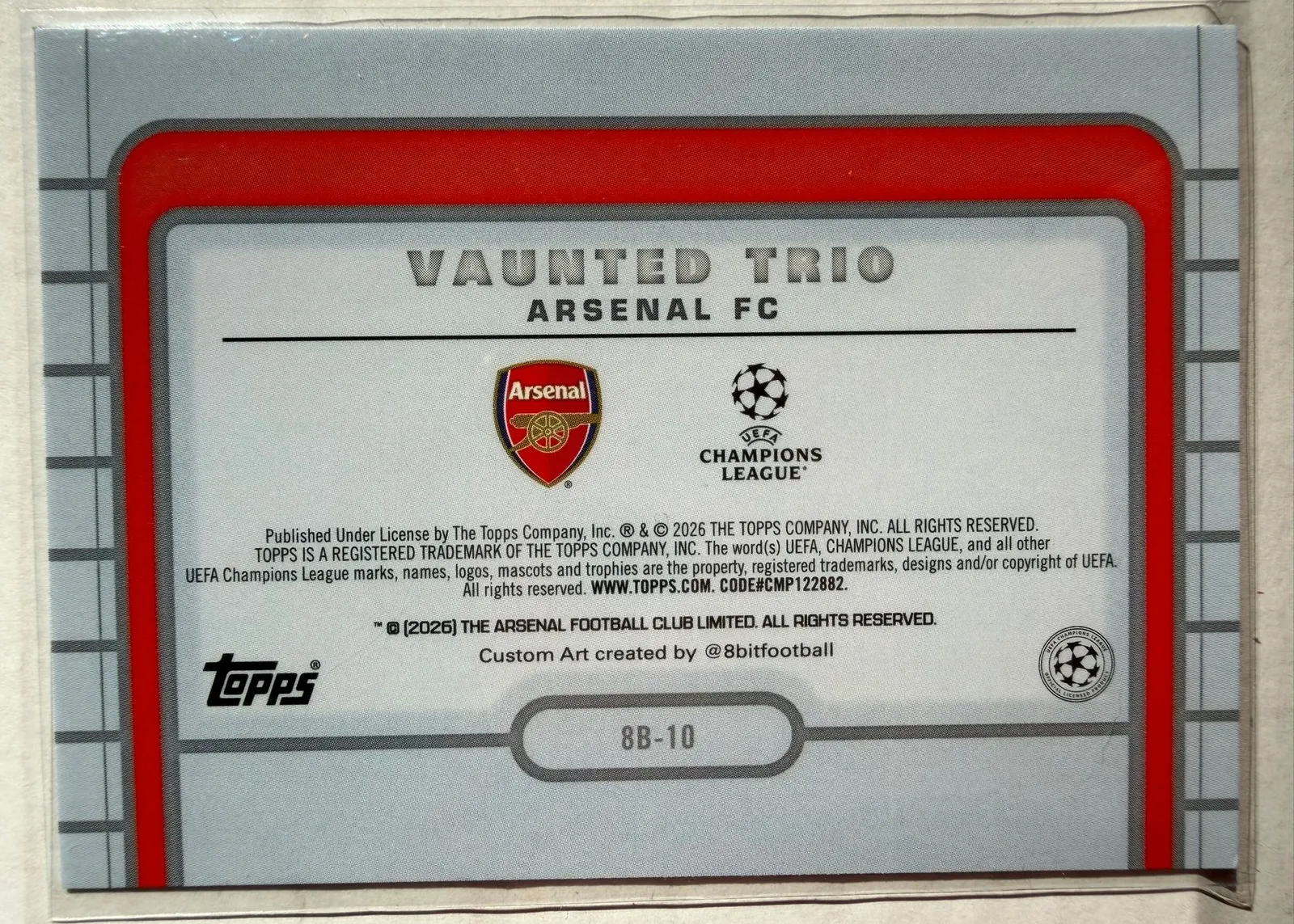 Arsenal, Vaunted Trio, Topps UEFA Club Competitions 2025/26 8-Bit Shots, karta 8B-10 — rewers w stylu retro konsoli z herbem Arsenalu i logo Ligi Mistrzów