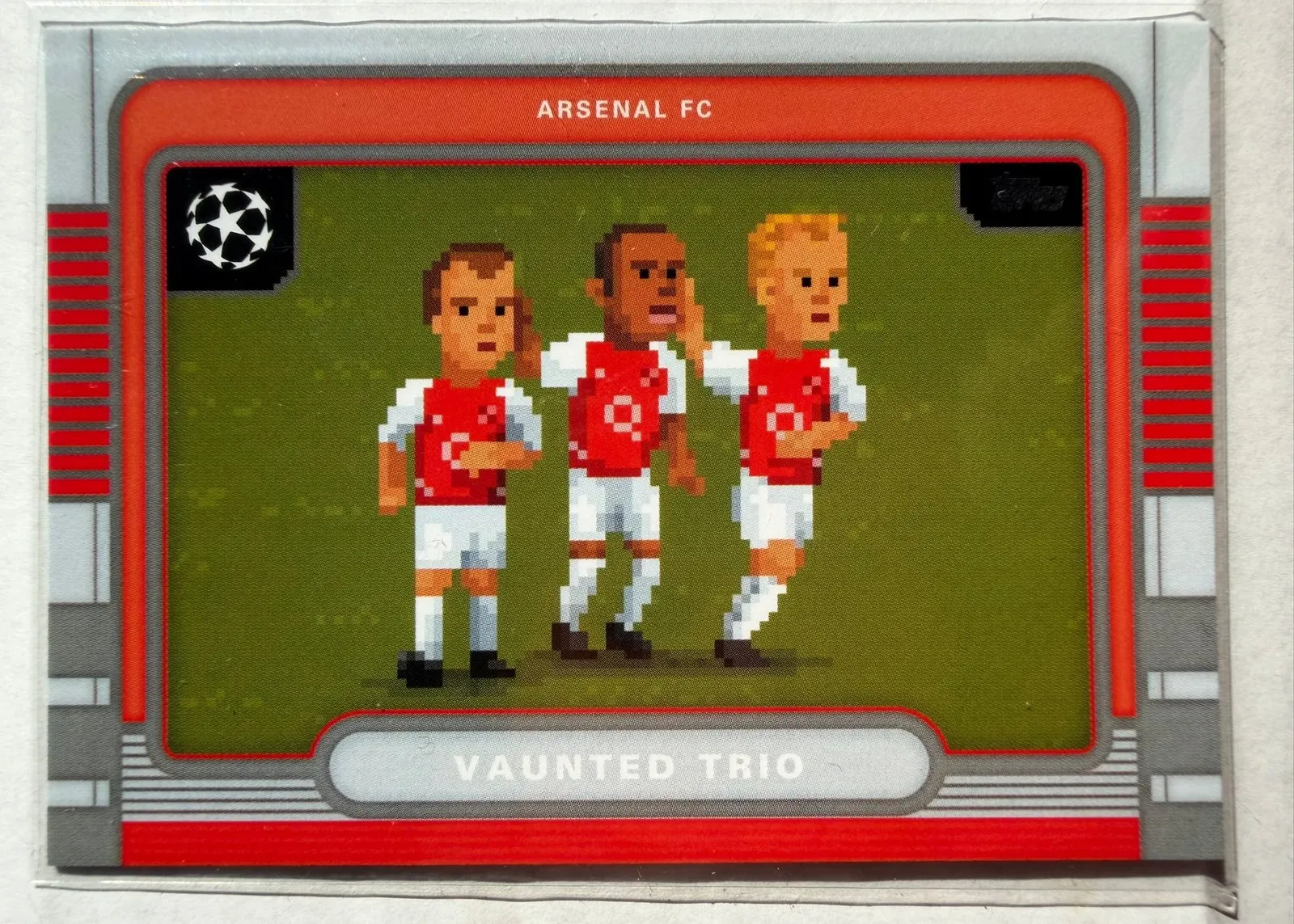 Arsenal, Vaunted Trio, Topps UEFA Club Competitions 2025/26 8-Bit Shots, karta 8B-10 — pozioma karta z trzema pikselowymi piłkarzami w czerwono-białych strojach Arsenalu