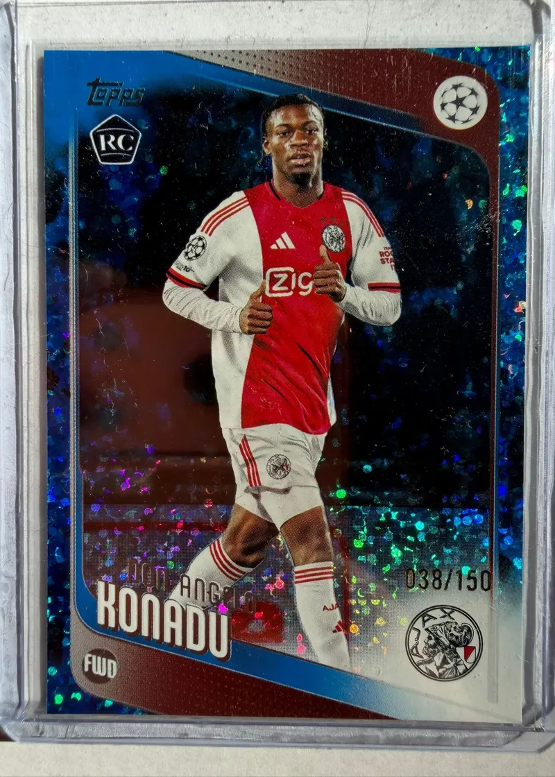 Don-Angelo Konadu, Topps UEFA Club Competitions 2025/26 Blue Inferno Holo, karta 173, numeracja 38/150 — awers z oznaczeniem RC, niebieskim holograficznym tłem i piłkarzem w biało-czerwonym stroju Ajaksu