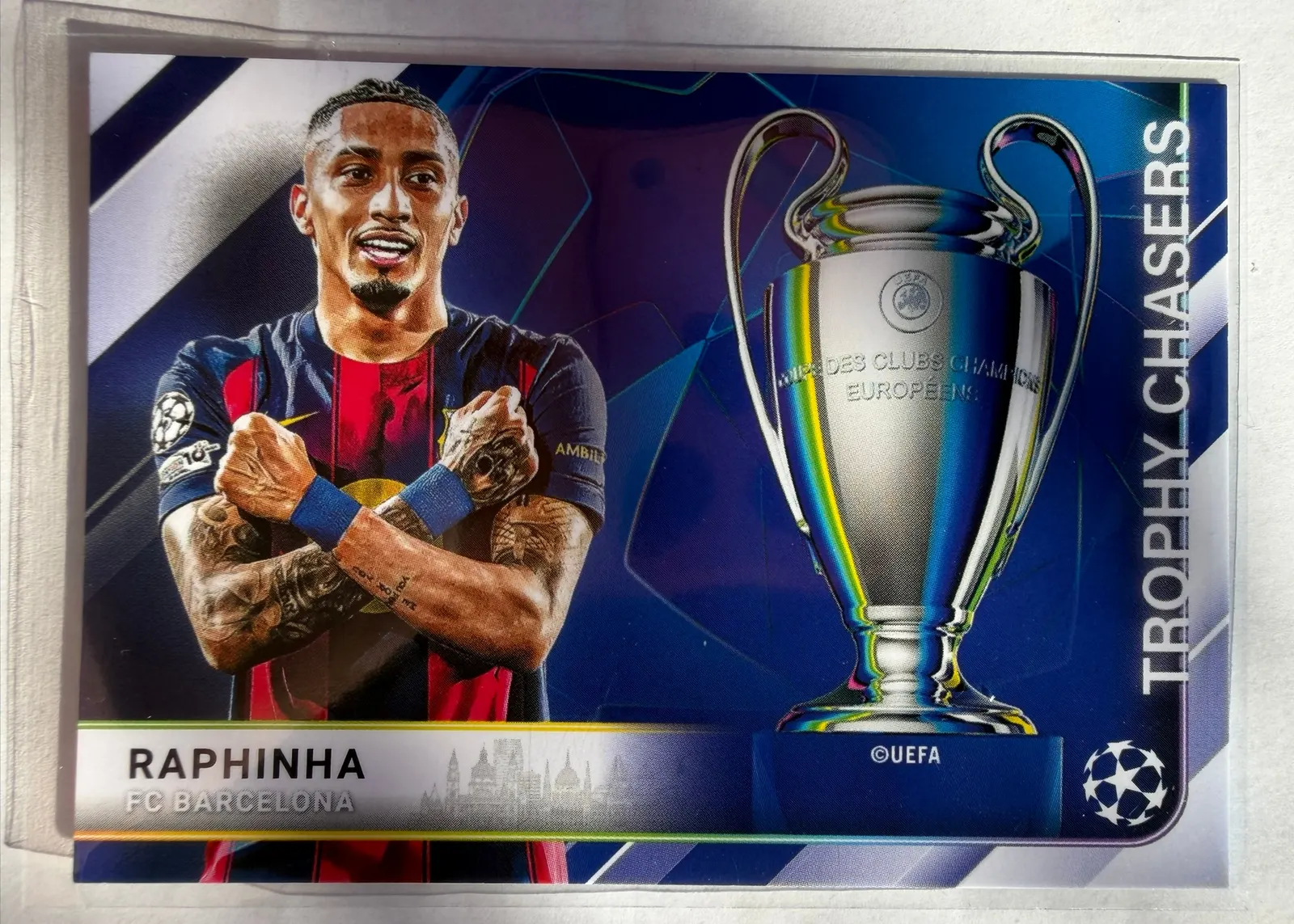 Raphinha, Topps UEFA Club Competitions 2025/26 Trophy Chasers, karta TC-9 — awers poziomy z zawodnikiem po lewej i pucharem Ligi Mistrzów po prawej