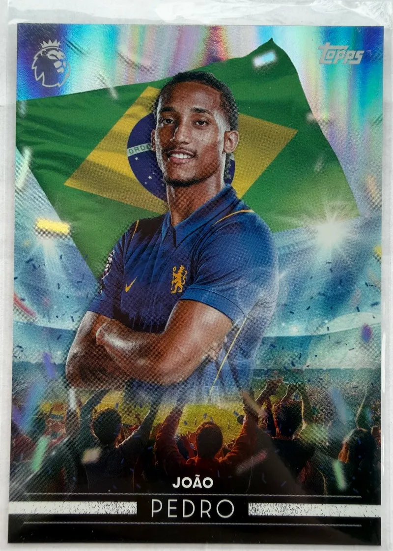 João Pedro, Topps Premier League 2026/27, insert Flying the Flag — awers z napastnikiem Chelsea w granatowym stroju na tle brazylijskiej flagi