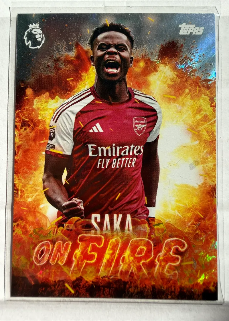 Bukayo Saka, Topps Premier League 2026/27 OF 7 On Fire — awers ze skrzydłowym Arsenalu na tle wybuchu ognia