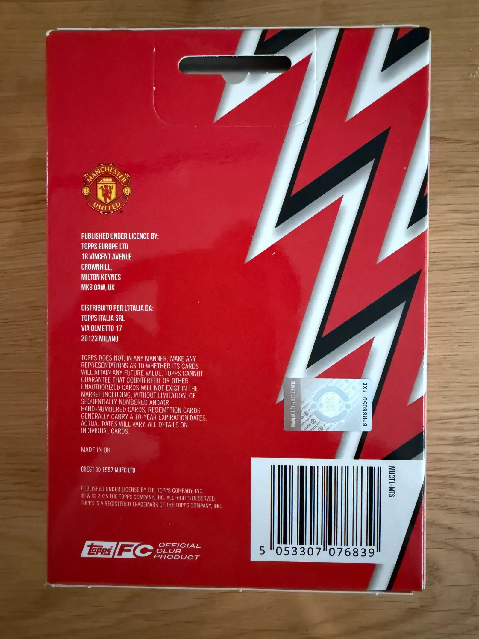 Topps Manchester United Collector Tin 2025/26, tył opakowania z danymi licencyjnymi Topps Europe, klubowym hologramem, kodem kreskowym i logo Topps FC Official Club Product