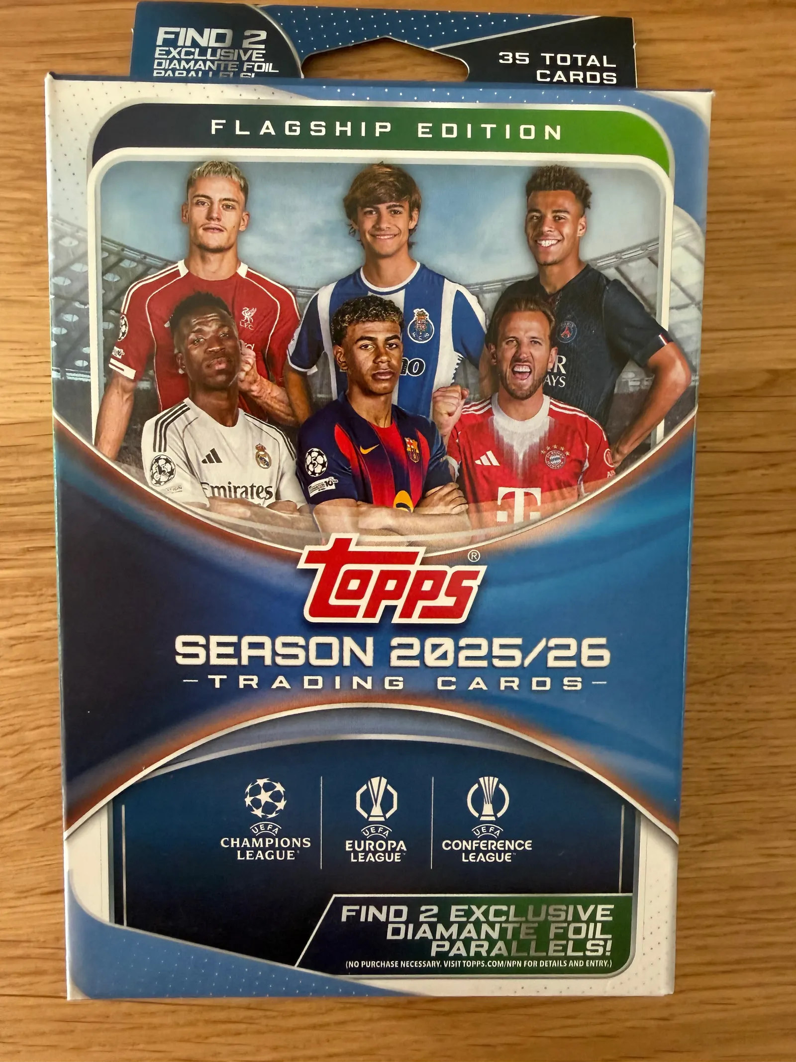 Topps UEFA Club Competitions Flagship Edition 2025/26, nieotwarty hanger box, front opakowania z zawodnikami i logo trzech rozgrywek UEFA